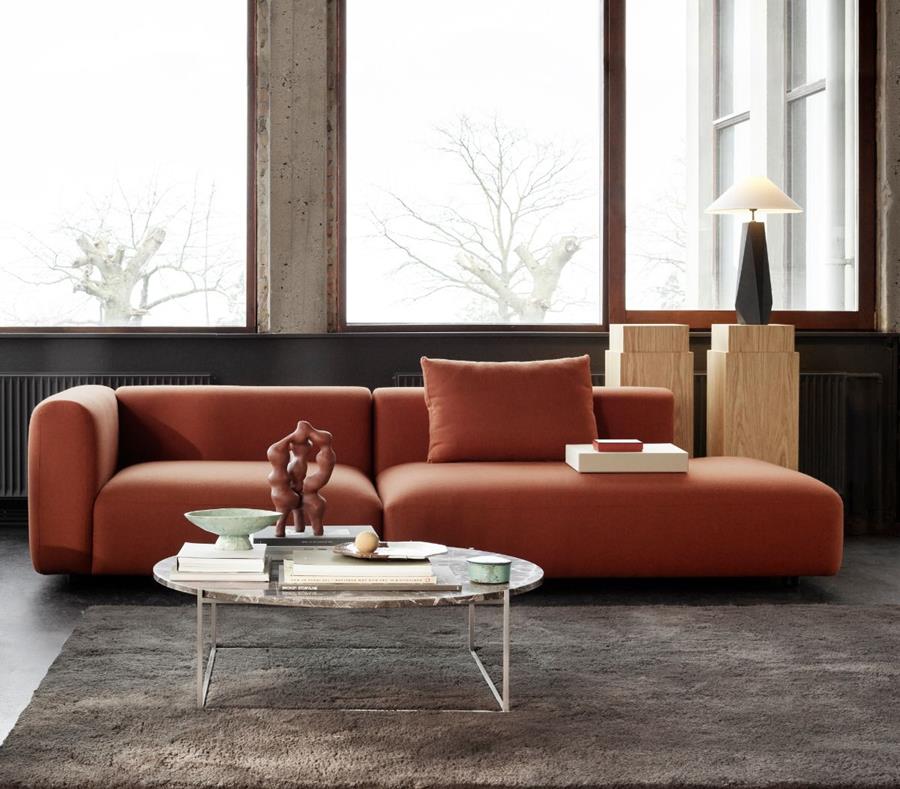 Lounge with a terracotta modular sofa and round coffee table by tall windows
