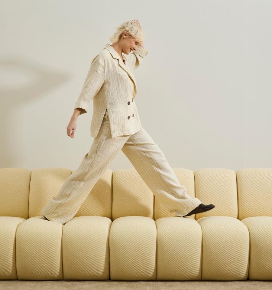 UMI wool: model stepping across a cream channel-tufted sofa
