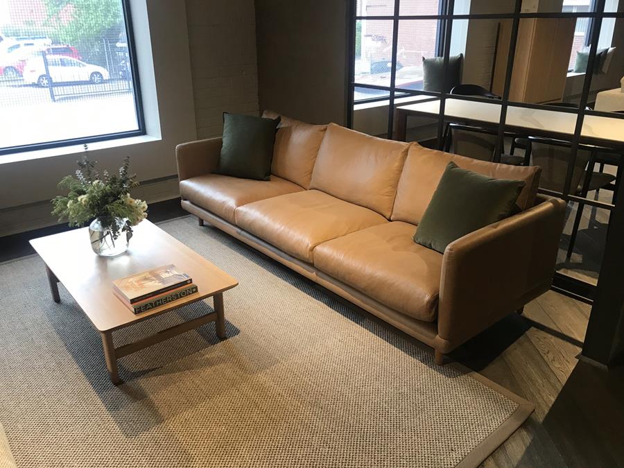 A tan Brusio leather sofa in a lounge with concrete walls
