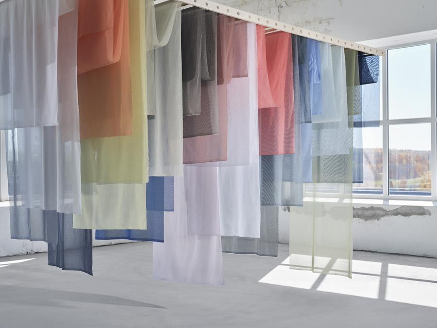 Layered sheer curtains in red, blue and green in a bright room