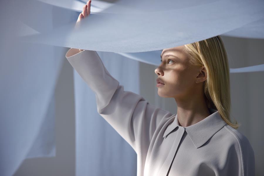 Woman lifting a sheer Svensson Airy curtain to the light
