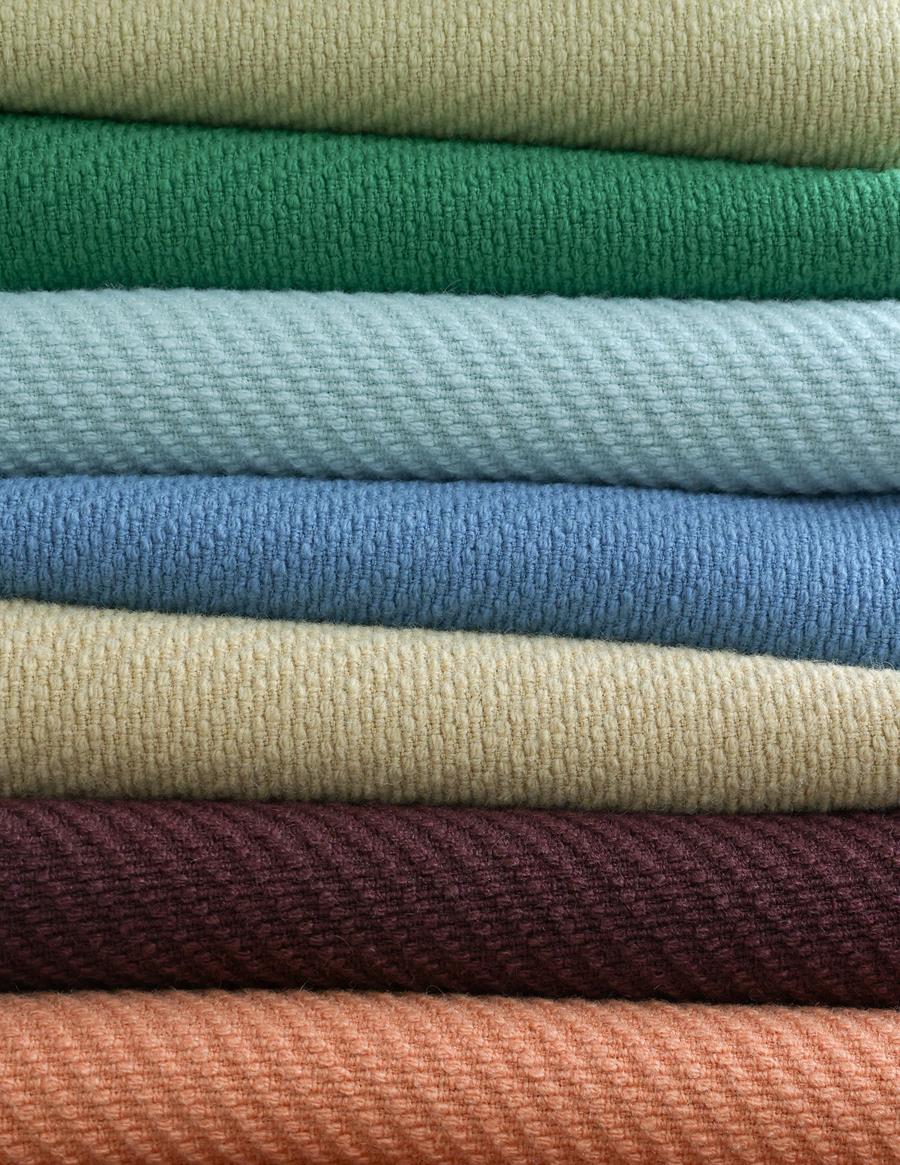 Stack of Gabriel twill fabrics in greens, blues, burgundy and coral