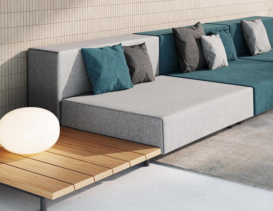 Glamp: grey outdoor velvet sofa with teal and charcoal cushions on a timber deck