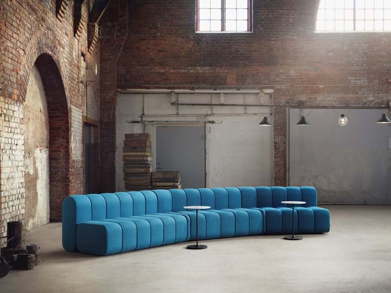 Long blue modular sofa in a brick warehouse