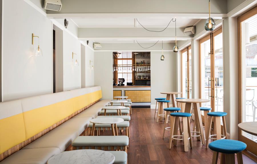 A long café banquette in yellow leather with blue stools