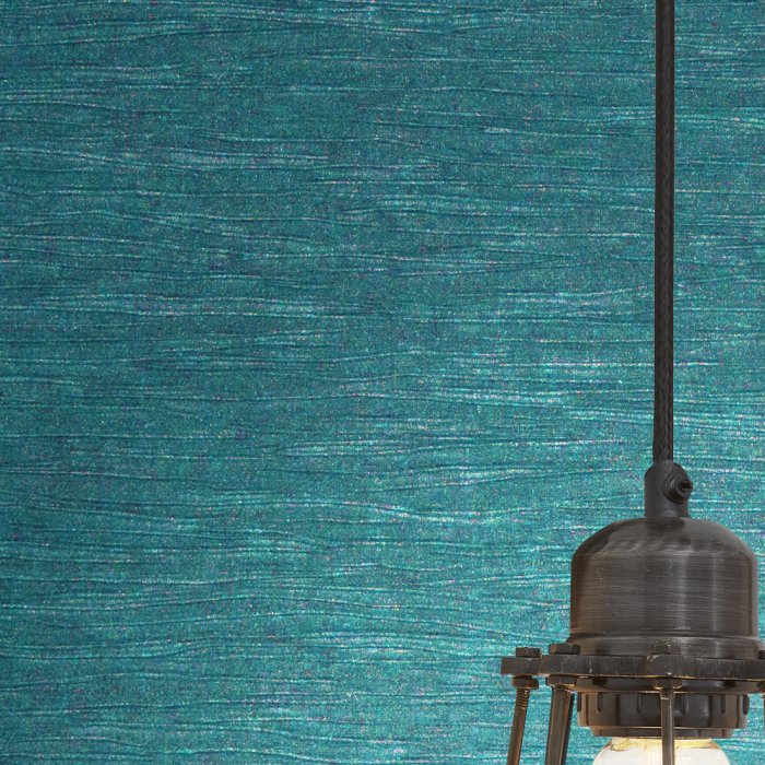 A teal textured wallcovering behind a pendant light