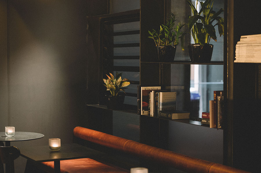 A dark bar with a long tan leather bench