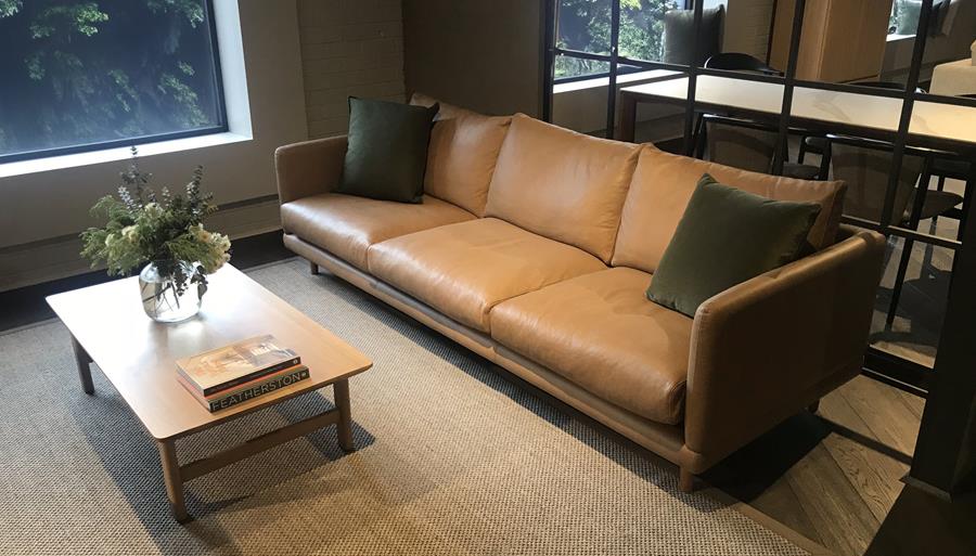 A tan leather sofa in a lounge with concrete walls