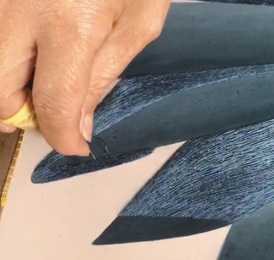 Close-up of hand embroidery on dark blue leaves