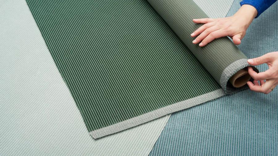 A hand unrolling green Designtex Velvet Corduroy