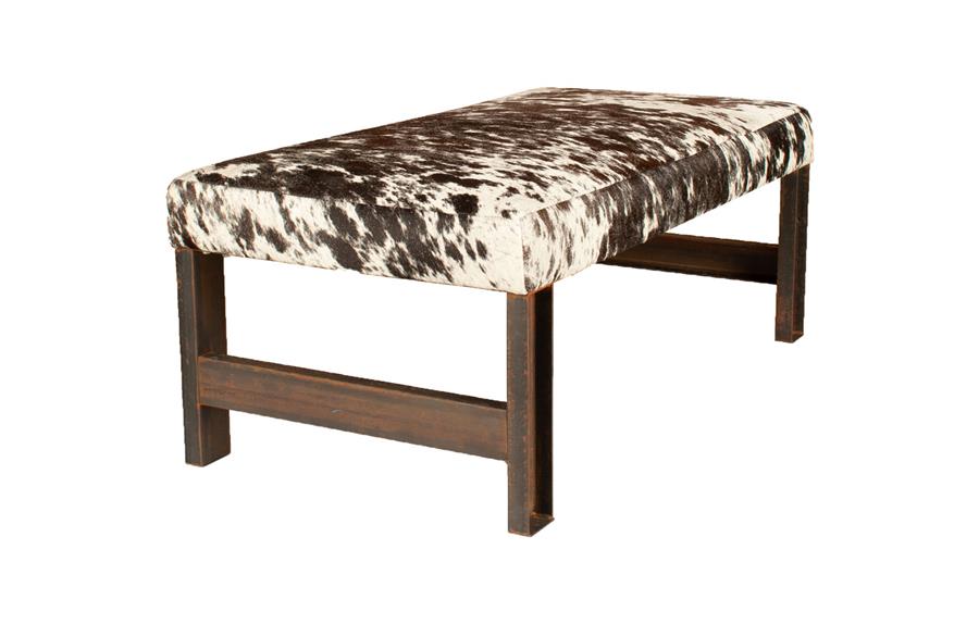 A bench in brown and white hair on hide on timber legs