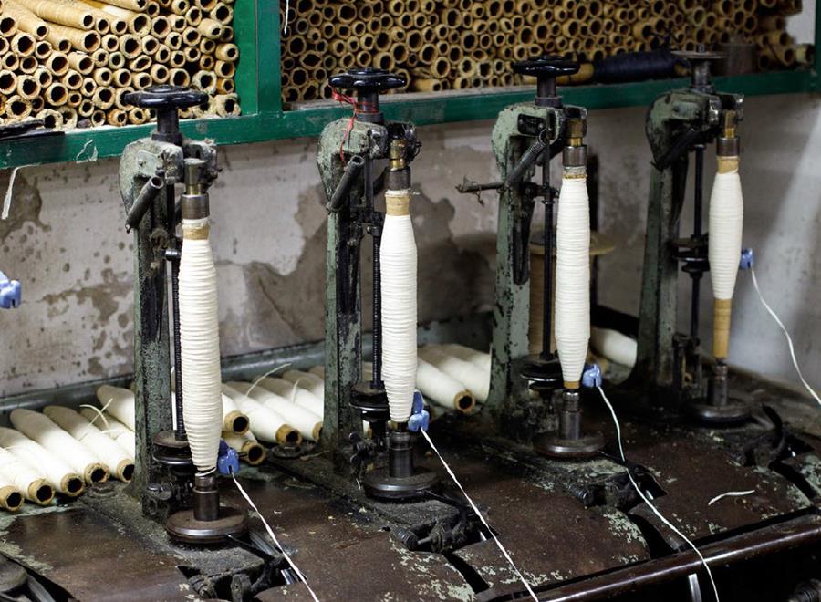 A row of old spinning machines winding white yarn