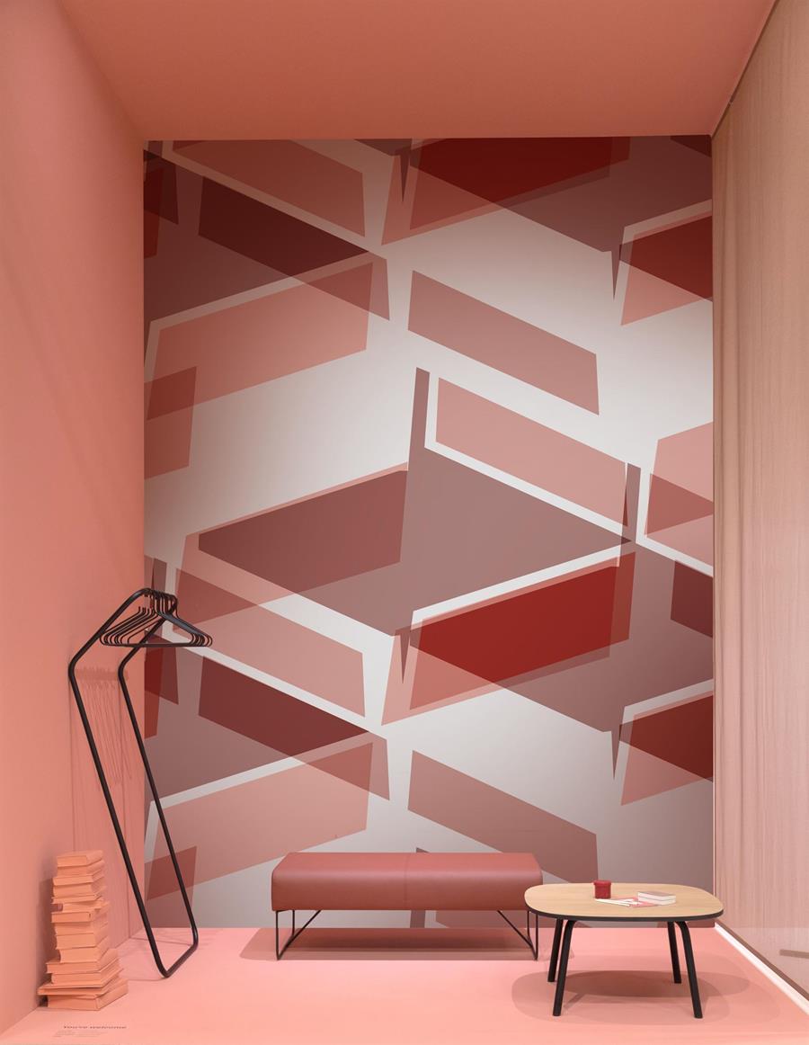 A pink geometric wallcovering behind a low bench