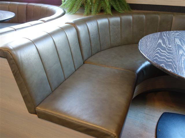 A curved leather booth around a round table