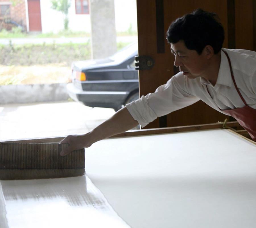 A craftsman smoothing a long white panel on a work table