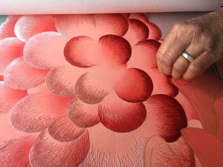 A hand shading coral pink petals on silk