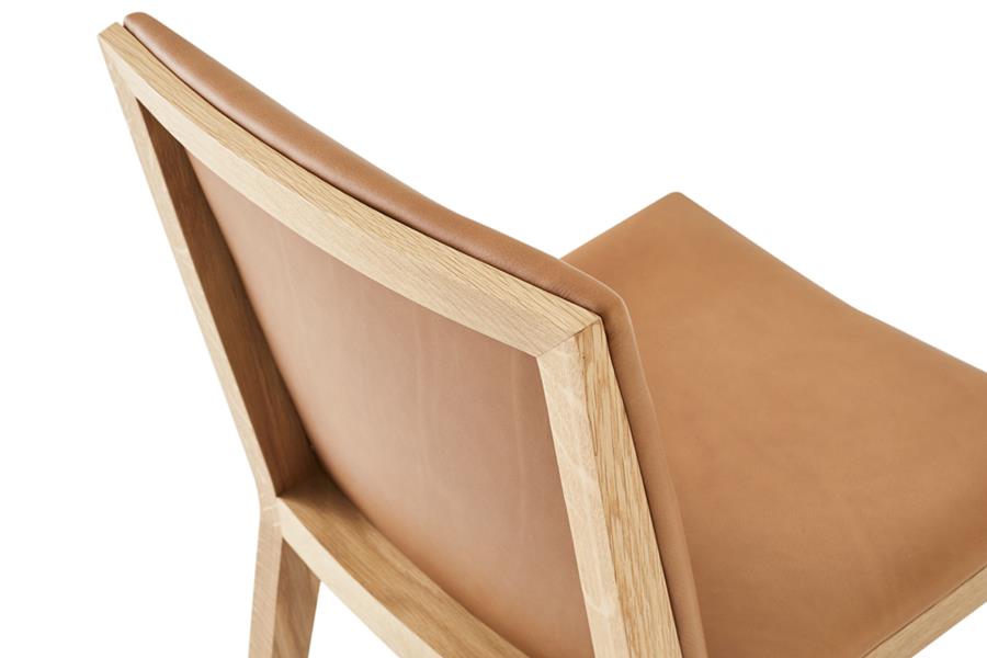 A timber chair with a tan leather seat and back