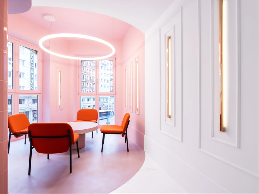 Pink room with orange upholstered chairs around a round table