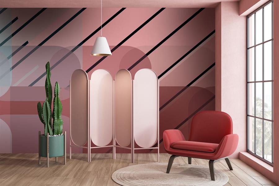 A wall in pink diagonal stripes behind a pink armchair