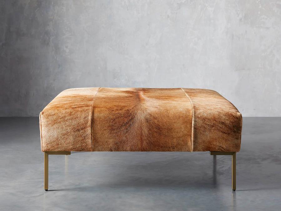 A bench upholstered in brown and white hair on hide