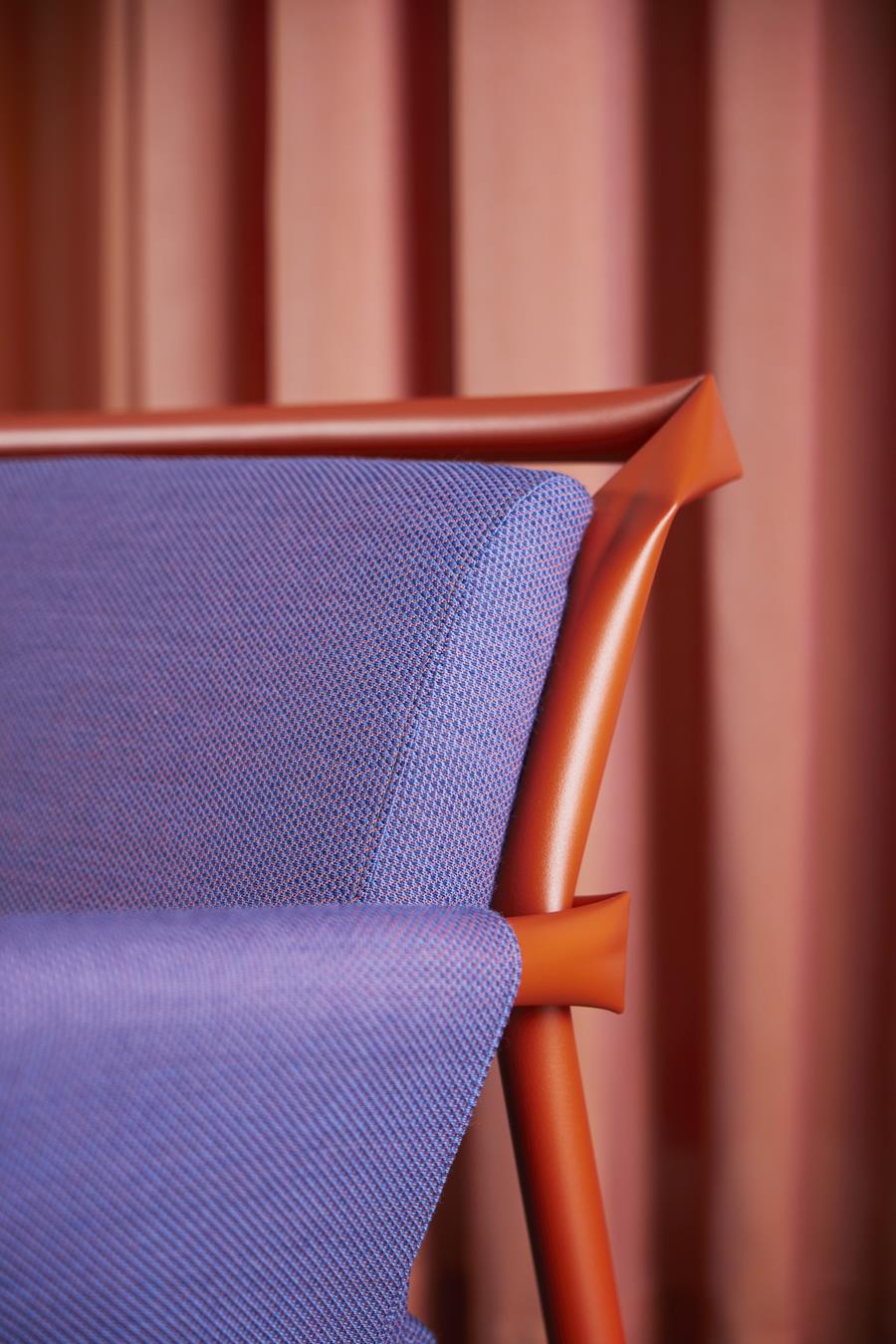 A chair seat in violet Svensson upholstery with an orange frame