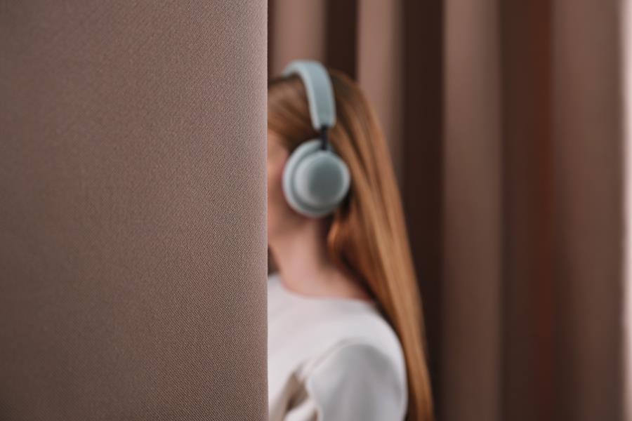 Woman in headphones beside a heavy brown Svensson curtain
