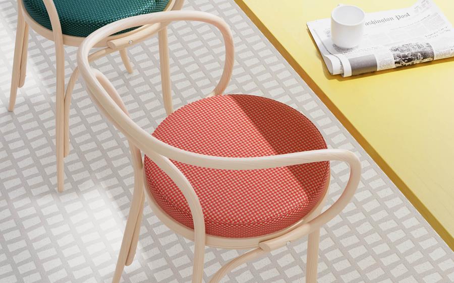 Bentwood chair with a coral cushion among Designtex outdoor fabrics