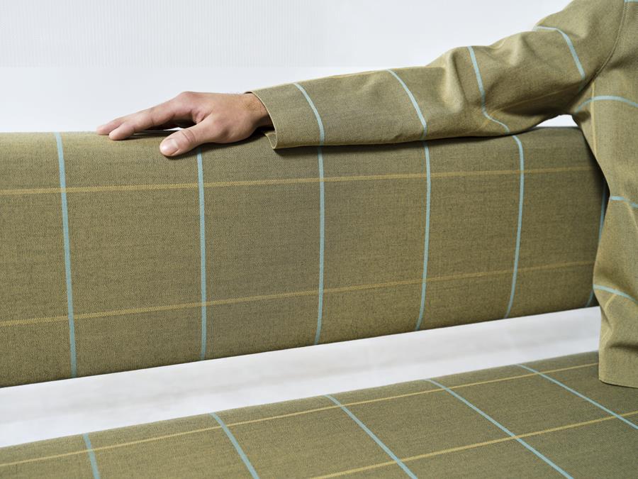 A hand resting on a bench in olive Svensson Club check