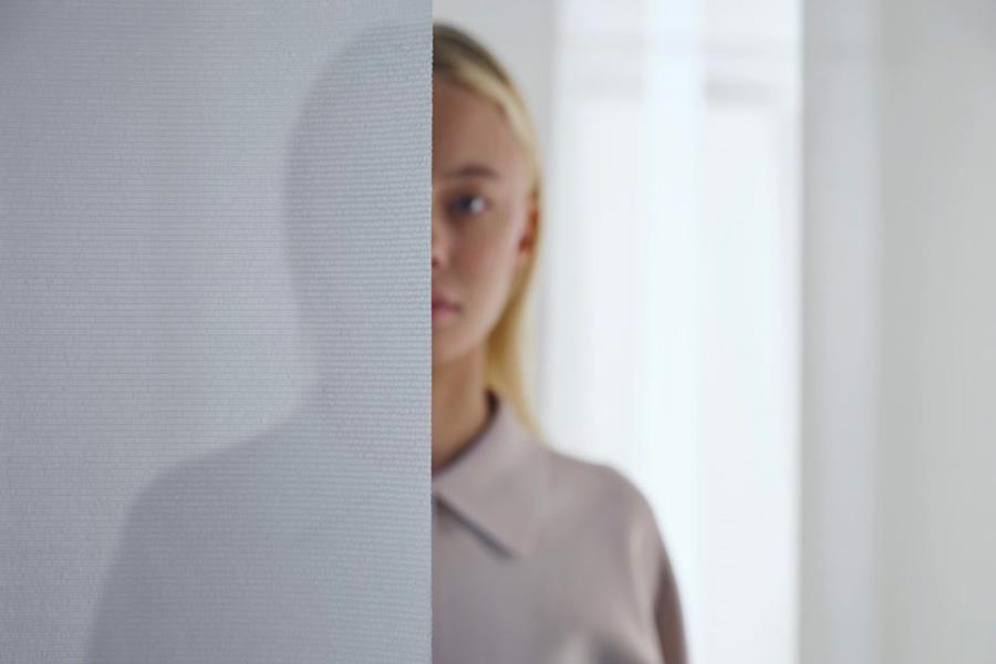 Woman standing behind a white sheer curtain