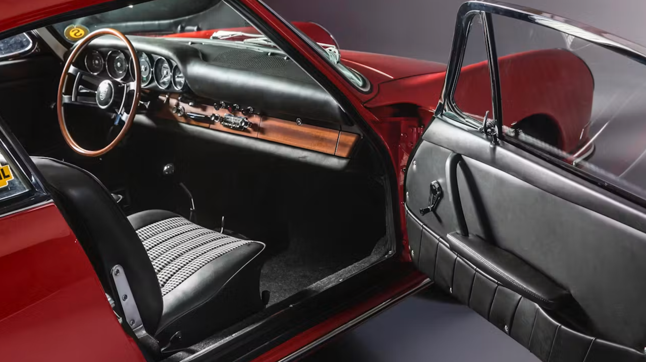 The red interior of a classic Porsche, its seats in black and white pepita check