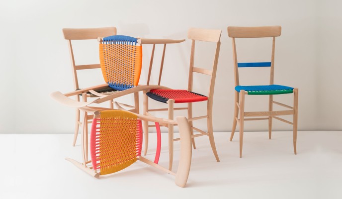 Light timber chairs in the Chiavari style, their woven seats orange, blue, red and green