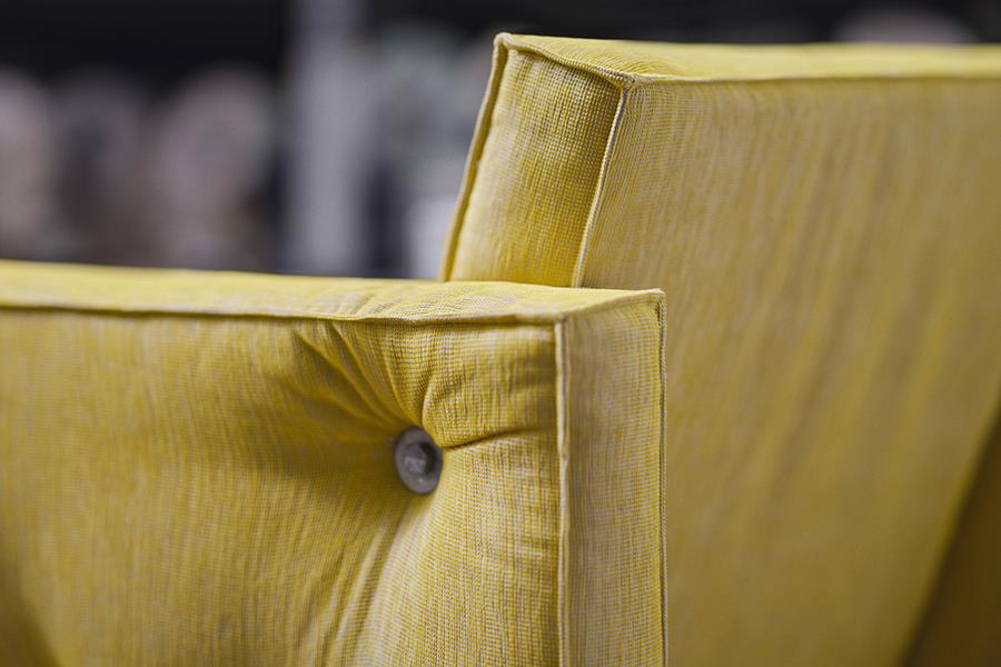 Close-up of a chartreuse Svensson upholstered chair with a button detail