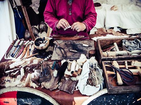 Hands working leather among old tools