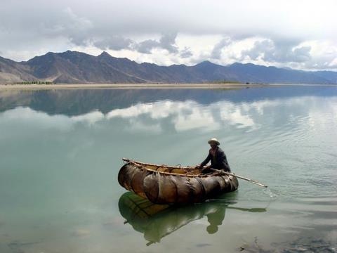 A small hide boat on a still mountain lake