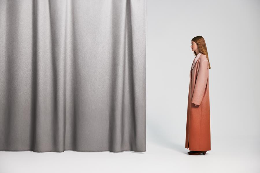 Ombre curtain graded from grey to white beside a woman in a long coat