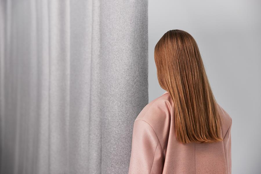 Woman in a pink coat beside a grey graded Svensson curtain