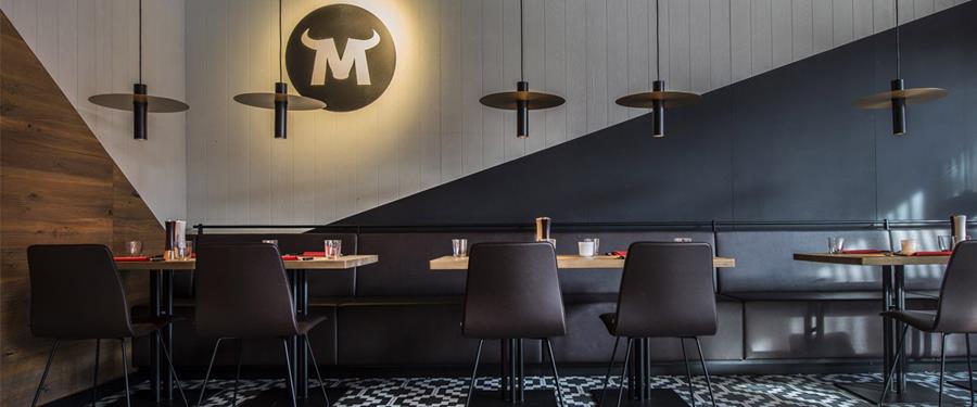 Restaurant with dark banquette seating and pendant lights