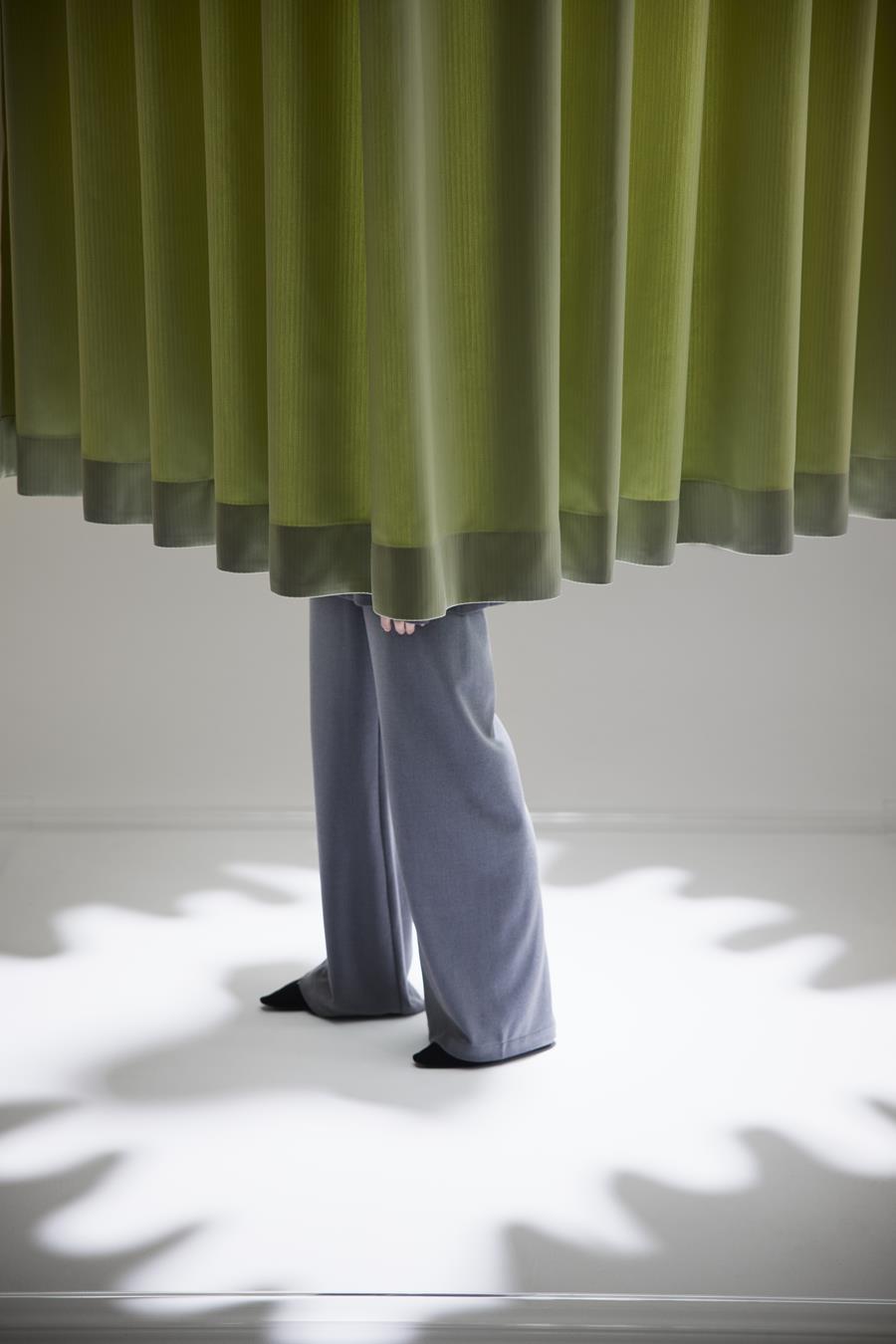 An olive Svensson curtain falling to the floor in a pool of light